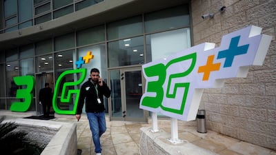 A Palestinian man speaks on his phone as he walks past a 3G sign outside the building of the Jawwal company, in the West Bank city of Ramallah, on January 24, 2018. Mohamad Torokman / Reuters