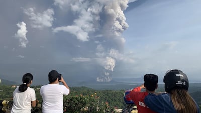 People take photos of a phreatic explosion from the Taal volcano as seen from the town of Tagaytay in Cavite province. AFP