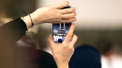 A worshipper takes a photo of the Kaaba. The number of international visitors has exceeded that of last year, despite the conflict in the Middle East. AFP