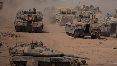 Israeli soldiers work on a tank in a staging area near the border with Gaza. AP