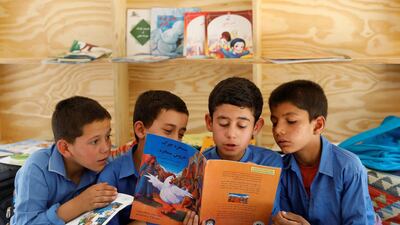 Boys read books inside a mobile library bus.