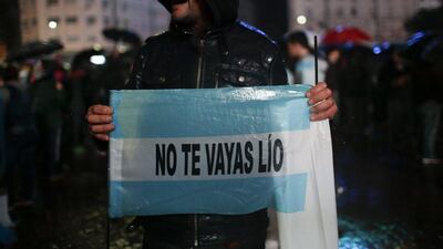 A vendor holds a flag that reads in Spanish “Lio don’t leave”.