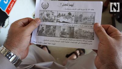 A Syrian man holds a leaflet stamped with the government forces' seal and dropped by helicopters flying over the Syrian city of Saraqib, southwest of Aleppo