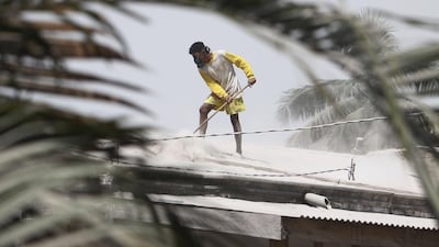 An Indonesian man cleans volcanic ash from a roof of a house after Mount Sinabung volcano spewed thick volcanic ash across the area the day before in Karo, North Sumatra. Kadri Boy Tarigan / AFP