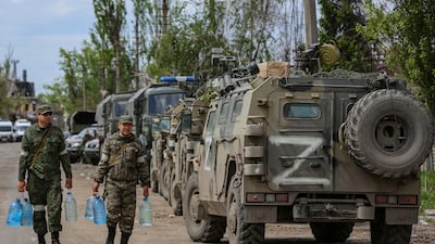 Members of the self-proclaimed Donetsk People's Republic forces carry water bottles as the evacuation of Ukrainian soldiers is carried out in Mariupo. EPA