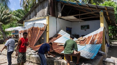 People collect their belongings from a damaged home off the southern island of Mindanao. Reuters