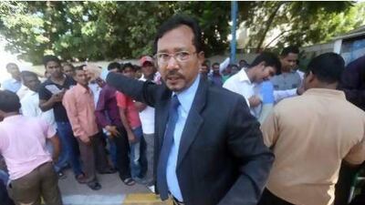 Zashim Uddin, the first secretary of the Bangladeshi embassy in Abu Dhabi, helps to direct citizens waiting in long lines yesterday to have their old handwritten passports replaced with modern digital ones. Sammy Dallal / The National