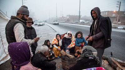 Residents in an outlying area gather by a roadside as snow falls. Reuters
