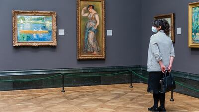 A woman wearing a face mask looks at paintings during preparations for opening at the National Gallery. EPA