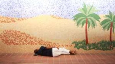 A man sleeps in a pedestrian underpass on the Corniche using his slippers as a pillow.