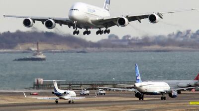 An Airbus A380 passenger jet, top, flies past commercial jets at Boston's Logan International Airport. US airfares are set to fall next year. Steven Senne / AP