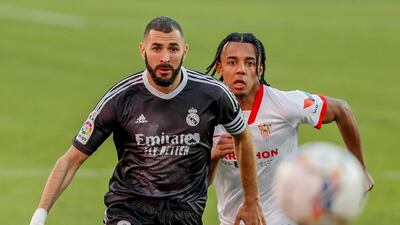 Real Madrid's Karim Benzema, left, challenges for the ball with Sevilla's Jules Kounde. AP