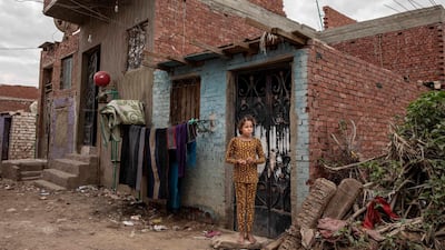 A girl waits outside her home in Cairo to see if she and her family will get a carton filled with food from the non-governmental organisation Resala Nour Ala Nour. Nariman El-Mofty / AFP