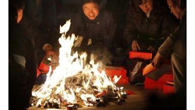 Relatives of people who died in the Shanghai apartment fire burn paper money for the deceased to use in the afterlife.