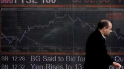 A man walks past an electronic display board showing the FTSE 100 share index in London.