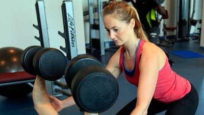 Alys Hannaway, a personal trainer, assists her client at a gym in Abu Dhabi.
