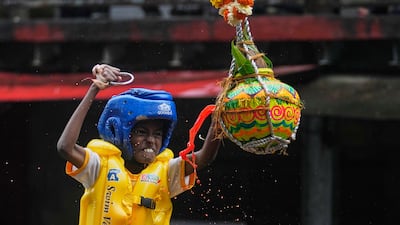 A boy tries to break an earthen pot filled with curd, after climbing on top of a human pyramid as part of celebrations to mark Janmashtami in Mumbai, India. AP