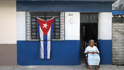 A woman sits in the doorway of her home, decorated with a Cuban flag in honor of the late Fidel Castro, in the town of Regla on the outskirts of Havana on November 27, 2016. Enric Marti/AP Photo