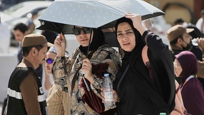 Worshippers share an umbrella outside the Grand Mosque. AP