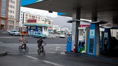 A couple of boys bike pass an Oman Oil petrol station in Muscat, Oman, on October 12, 2011. Silvia Razgova / The National