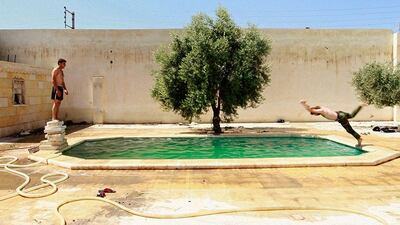 A Free Syrian Army fighter dives into a swimming pool, as his fellow fighter watches him in Aleppo, Syria. Hamid Khatib / Reuters