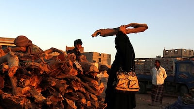 A Yemeni woman carries a bundle of firewood amid a severe cooking gas shortage, at a firewood market in Sana'a, Yemen. EPA