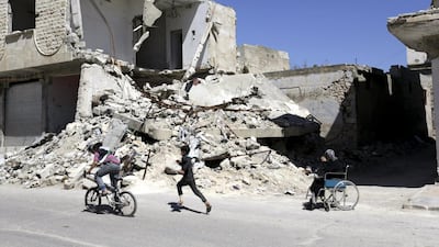 A woman sits on a wheelchair near a damaged building, as a boy follows another one riding a bicycle in the rebel-controlled town of Maaret Al Numan in Syria's Idlib province on April 1, 2016. Khalil Ashawi/Reuters