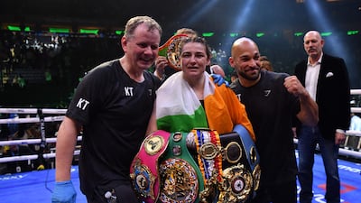 Katie Taylor celebrates with her belts alongside manager Brian Peters and coach Ross Enamait. AFP