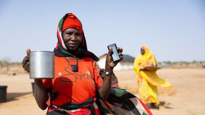A Sudanese refugee poses for a photo with some of her belongings in the Farchana refugee camp
