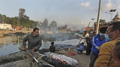 Shankar Pradhan, left, brings the bodies of his relatives who died in the earthquake for cremation on the banks of Bagmati River, near a temple in Kathmandu. Manish Swarup / AP Photo