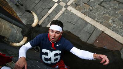 A mozo is squashed by a bull against the wooden barrier. EPA