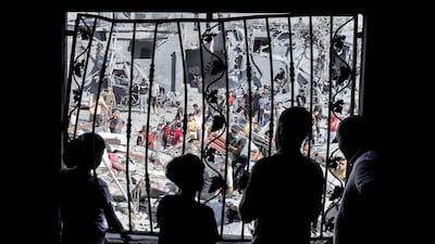 People stand behind the metal mesh covering a window of a building that was hit by Israeli strikes in Rafah in the Gaza Strip. AFP