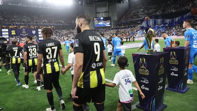 Al Ittihad's Karim Benzema walks out with a young mascot before the match. Reuters