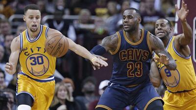Golden State Warriors’ Stephen Curry, left, knocks the ball loose from Cleveland Cavaliers' LeBron James, centre, in the first half of an NBA basketball game, Monday, Jan. 18, 2016, in Cleveland. Andre Iguodala is at right. (AP Photo/Tony Dejak)