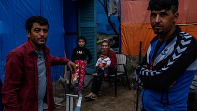 Migrants stand outside their tent near the refugee camp on the Greek island Samos, on November 13, 2019. AFP / ANGELOS TZORTZINIS