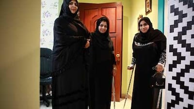 Mariam al Ahmadi, left, started the special needs committee and is currently trying to raise money to purchase equipment, including wheelchairs and crutches, needed by members of the community such as Aisha Esa, right, who suffers from polio.