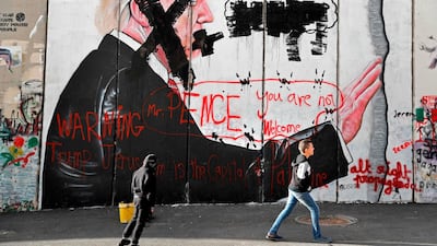 Palestinian children walk past vandalised graffiti depicting US President Donald Trump and slogans against US Vice President Mike Pence painted on Israel's controversial separation barrier in the West Bank city of Bethlehem during clashes with Palestinian protestors near an Israeli checkpoint on December 7, 2017. AFP / THOMAS COEX