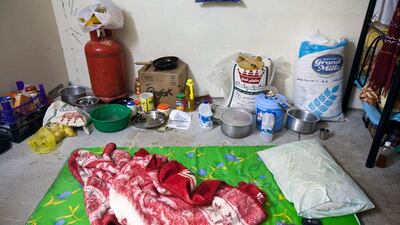 Cooking utensils, food and bedding sit on the floor of a room shared by seven labourers.