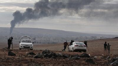 Members of the media on a hilltop on the outskirts of Suruc, at the Turkey-Syria border, watch as smoke from a fire rises following a strike in Kobani, Syria. Lefteris Pitarakis / AP Photo