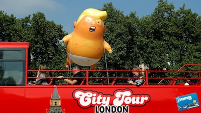 Demonstrators float the Trump blimp behind a red tourist bus. Rueters