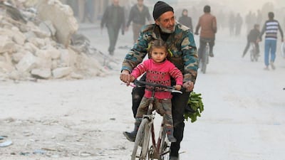 A man cycles with his daughter in a rebel-held area of besieged eastern Aleppo on November 23, 2016. Abdalrhman Ismail / Reuters