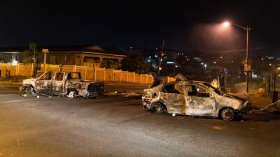The charred remains of two vehicles are seen in Phoenix Township, North Durban, on July 15, 2021 after days of violence in the community. - Armed community members and vigilante groups have stepped in to tackle unrest in South Africa, taking matters into their own hands and sometimes stoking violence as security forces struggle to restore order. Understaffed and heavily reliant on private security companies, the police was rapidly overwhelmed when riots and looting first flared last week in the southeastern province of KwaZulu-Natal (KZN), sparked by the jailing of graft-accused former president Jacob Zuma.