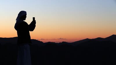 A visitor takes photos on Jebel Jais as the sun rises over Ras Al Khaimah. Pawan Singh / The National