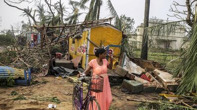 A woman pushes a bicycle past the wreckage of a shop, after Cyclone Fani passed through the Puri district of Odisha, India. Dhiraj Singh / Bloomberg