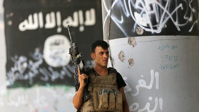 A member of Iraqi counterterrorism forces stands guard near Islamic State militant graffiti in Fallujah, Iraq. Hadi Mizban / AP Photo