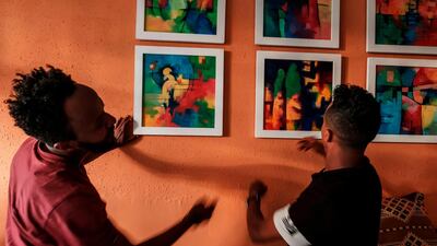 Eritrean painter Noah Mulubrhan arranges framed paintings with staff at a coffee shop as he prepares an exhibition of his paintings in that shop in Addis Ababa. AFP