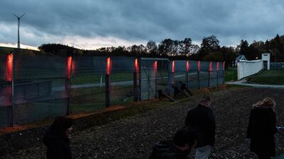 Visitors pass by illuminated border fence at former east German-west German borderline, part of German museum in Moedlareuth, Germany. EPA
