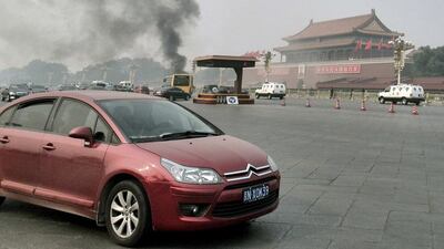 Vehicles travel along Chang'an Avenue as smoke rises from Beijing’s Tiananmen Square. Reuters