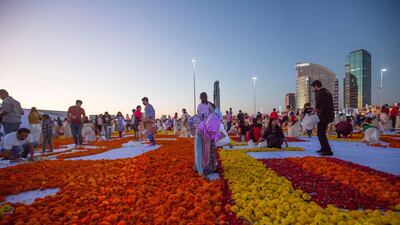 Thousands of volunteers laying out fresh flowers in an attempt to create the world's largest fresh flower carpet with the theme of Tolerance to highlight the UAE as a global capital for tolerance at Dubai Festival City. Leslie Pableo for The National