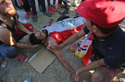 Iraqi men try to help a protester wounded during a demonstration in Baghdad's central Khellani Square on October 4, 2019. AFP